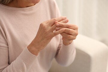 Mature woman suffering from pain in hand indoors, closeup. Rheumatism symptom - obrazy, fototapety, plakaty
