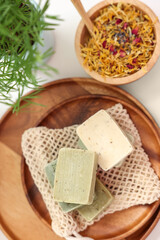 Soap bars and dry flowers on white table, flat lay. Spa time