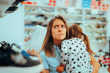 Funny Mom Trying to Buy Herself Sports Shoes. Busy mother caring for her child while shopping 
