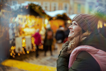happy woman at christmas fair in city looking into distance