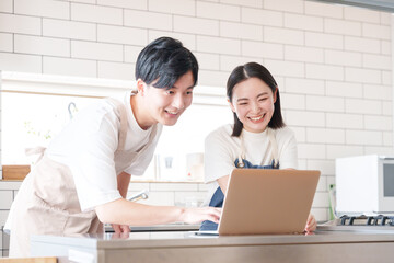 Obraz premium キッチンでパソコンを見て話す男女