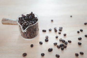Coffee beans in a glass container cup and scattered coffee beans on ground