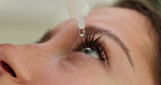 Closeup view of woman using eye drops