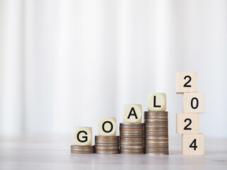 Wooden block with word GOAL on stack of coins and number 2024. The concept of saving money for Business achievement goal, Financial, Investment and Business growing in new year 2024.