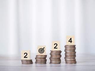 Wooden block with number 2024 on stack of coins. The concept of saving money for business...