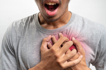 Young man having heart ache, holding hand on chest. Heart attack or stroke. risk of coronary heart...