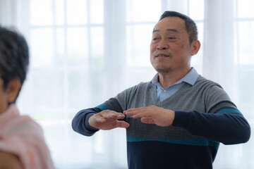 Portrait of elderly smiling Asian woman and people aerobics in nursery house. Seniors are moving their body arms and shoulders for a healthy life. retired people activities group concept.