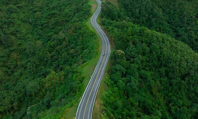 Aerial view of road dark green forest Natural landscape and elevated traffic roads Adventure travel and transportation ideas for the environment	