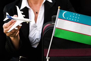 business woman holds toy plane travel bag and flag of Uzbekistan