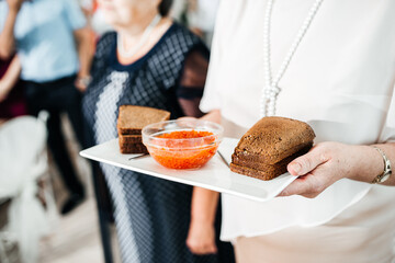 The groom's mother holds red caviar with bread at the wedding