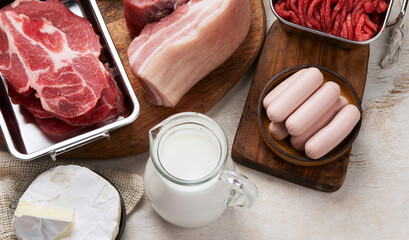 Saturated fats on tables. Raw meat, sausages, cheese, butter. Bad food concept