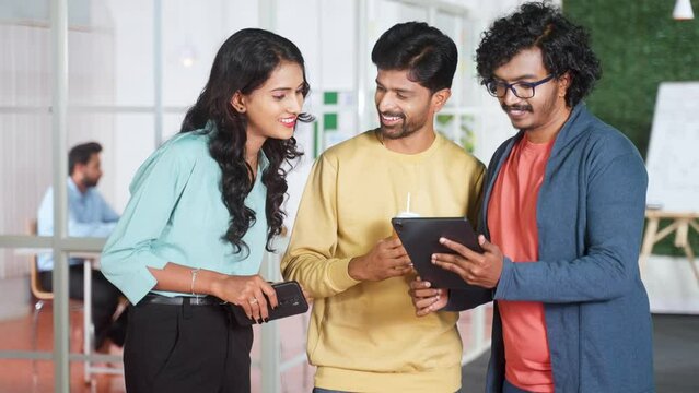 group of young coworkers at office discussing from tablet at office corridor - concept of startup workplace, team collaboration and colleague communication or interaction.