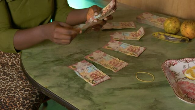 slow motion black female african woman organised paper bills money Ghanaian cedi currency of Ghana in a table in her house for paying taxes to government