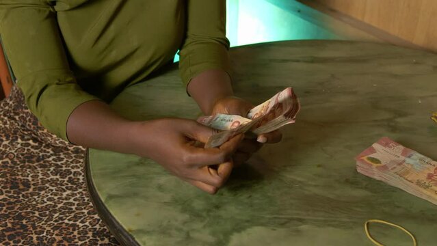black African female woman counting banknotes of Ghanaian republic currency cedi in her house, africa poverty corruption concept