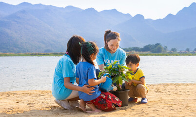 Team of volunteer worker group teaching children to planting tree in charitable social work on...