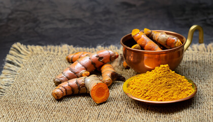 Ginger root and ginger powder in copper bowl on jute cloth
