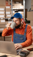 Smiling young Caucasian man drinking coffee while enjoying morning at work in a delivery service...