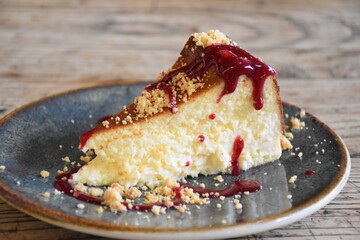 Raspberry sauce baked cheesecake on a blue plate, on the wooden table 
