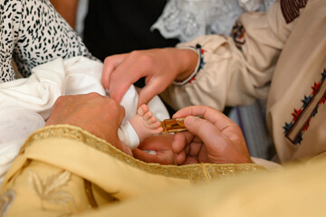 The priest performs the rite of baptism of the child and anoints the leg with holy myrrh.
