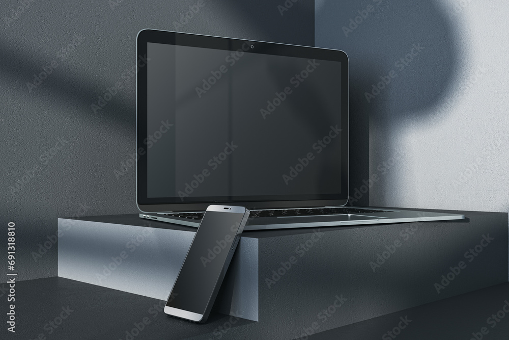 Poster close up of empty laptop and smartphone on dark gray desk. concrete wall background, shadows and ped