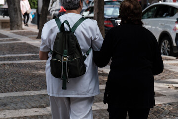 Fototapeta premium Osuna, Sevilla, cuidadora de anciana, paseando a mujer mayor, cogidas del brazo, vistas de espaldas