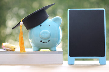 Graduation hat on piggy and stack of coins money on natural green background, Saving money for education concept