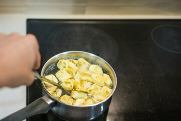 Ravioli with cottage cheese and spinach boiling in water inside a metal saucepan.