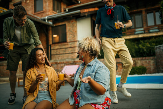 Friends with different backgrounds sharing stories, enjoying cool drinks, and making memories at a laid-back pool party