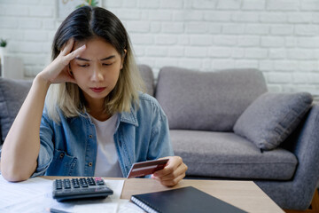 Stressed Asian woman with credit card debt and huge bills at home