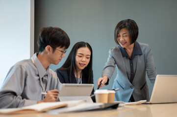 A professional senior Asian female boss is coaching to her employees in the meeting.