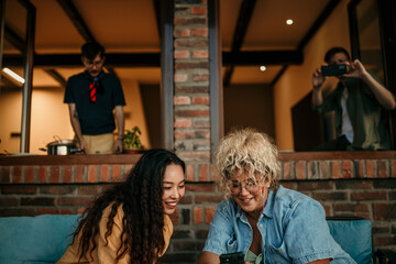 Obraz premium Diverse friends enjoying backyard vibes: lively conversation, a guys cooking, and a women using a phone