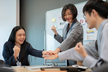 Group of diverse businesspeople are putting their hands together above a meeting table.