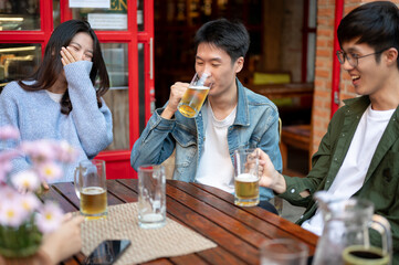 Group of happy friends are enjoying talking and drinking beers while hanging out at a restaurant.