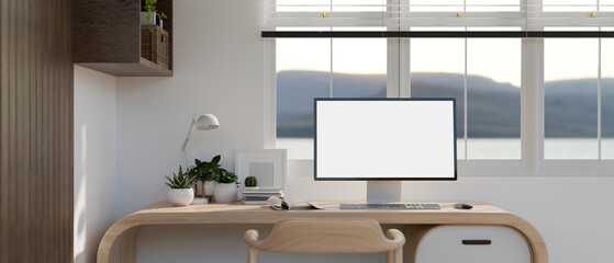 PC computer white screen mockup on a modern wooden desk against the window in a modern room.