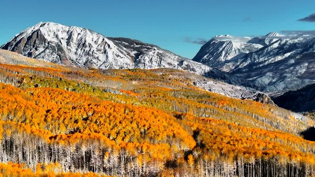 Kebler Pass aerial cinematic drone morning light Crested Butte Gunnison Colorado seasons crash early fall aspen tree red yellow orange forest winter first snow Rocky Mountain peaks circle right motion