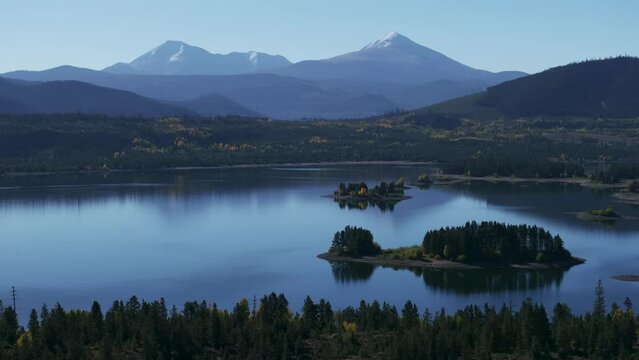 Early fall colors Lake Dillon islands Colorado aerial cinematic drone morning view Frisco Breckenridge Silverthorne Ten Mile Range calm reflective water yellow Aspen trees to the right movement