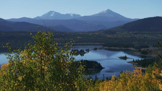 Early fall colors Aspen trees Lake Dillon islands Colorado aerial cinematic drone morning view Frisco Breckenridge Silverthorne Ten Mile Range calm reflective water yellow dolly jib upward movement