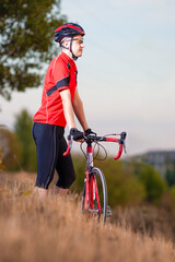 Portrait of Man Cyclist Relaxing with Road Bicycle Outdoors on Nature Background. Equipped with Professional Outfit.
