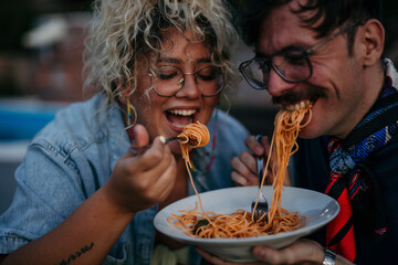 Loving diverse couple enjoying eating and drinking together during a yard party