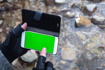 Adult Woman Hands Using a Smart Phone in Nature with Green Screen Over a Water stream