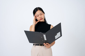 A tired businesswoman reading documents in a binder with a disappointed face and feeling headache.