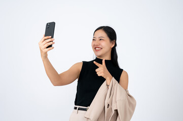 A cheerful Asian businesswoman is pointing her finger at her smartphone screen while using it.