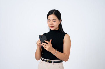 An attractive Asian woman using her smartphone, standing against an isolated white background.