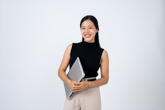 A beautiful and confident Asian businesswoman holding a laptop computer, isolated white background.