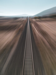 Motion blur view taken by drone of train track passing through arid land
