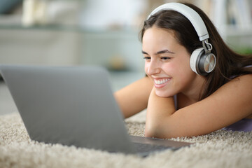Happy woman with headphone checks laptop