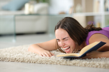 Woman on the floor laughing hilariously reading a book