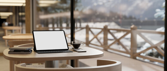 A digital tablet mockup on a table near by the window in a beautiful cosy coffee shop. workspace