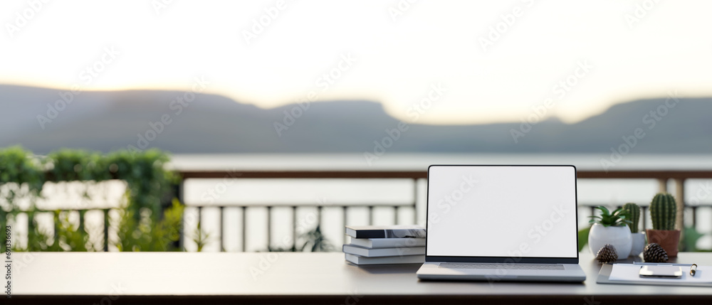 Poster front view of a workspace on a balcony with a white-screen laptop computer mockup on a table.