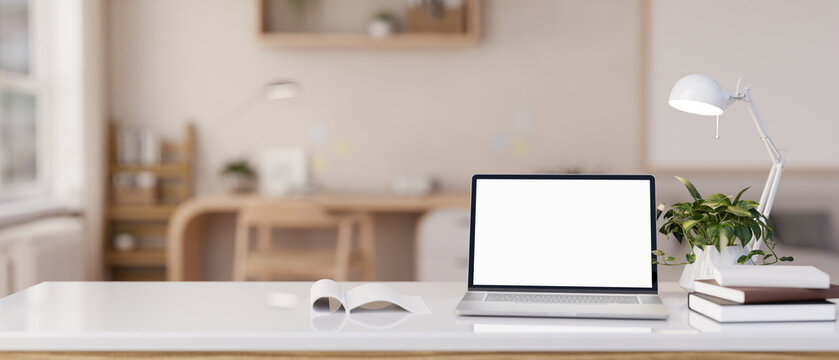 Close-up image of a white-screen laptop computer on a white tabletop in a modern Scandinavian room.